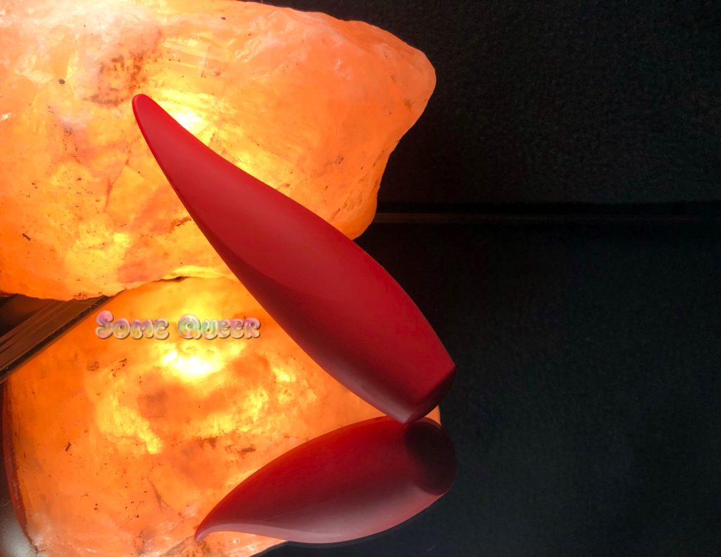 Red Hot Ember by Calexotics propped against a salt lamp, all of it on top of a mirror.