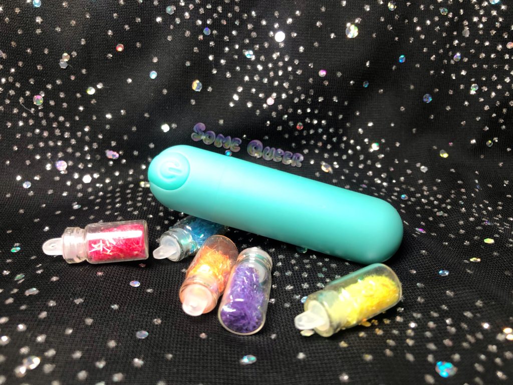 BMS Essential PowerBullet In teal, surrounded by little glass bottles of decorative glitter